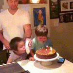 Papá e hijos soplando la vela en cumpleaño